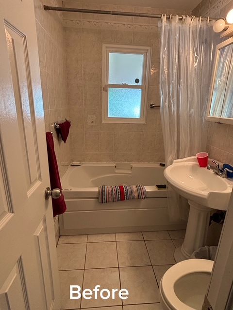 Small beige bathroom with a tub-shower, pedestal sink, toilet, and red accents; labeled “Before”