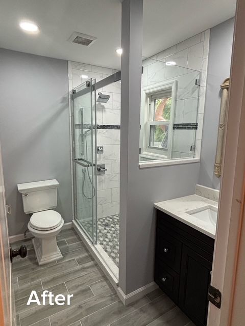 Small gray bathroom with toilet, glass shower, and vanity; labeled “After”