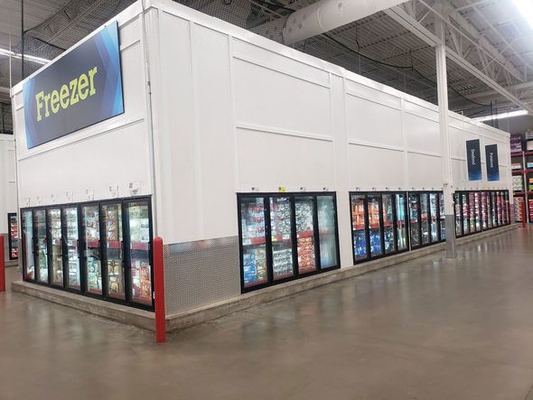 A freezer section of a grocery store with a lot of refrigerators.