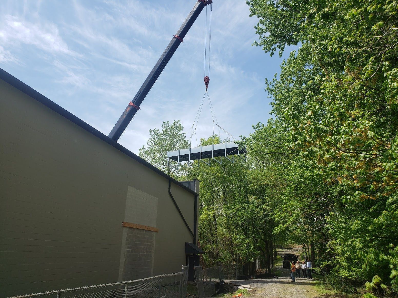A crane is lifting a large piece of metal over a building.