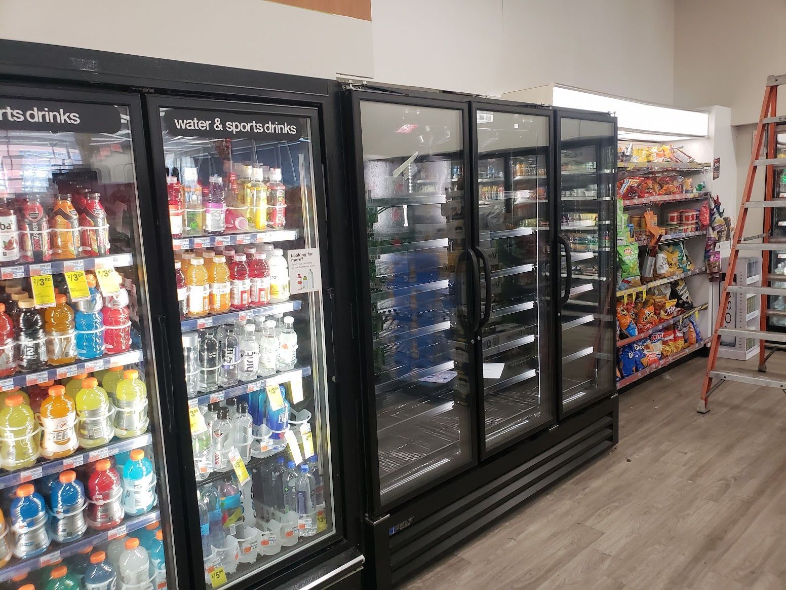 A row of refrigerators filled with drinks in a store.