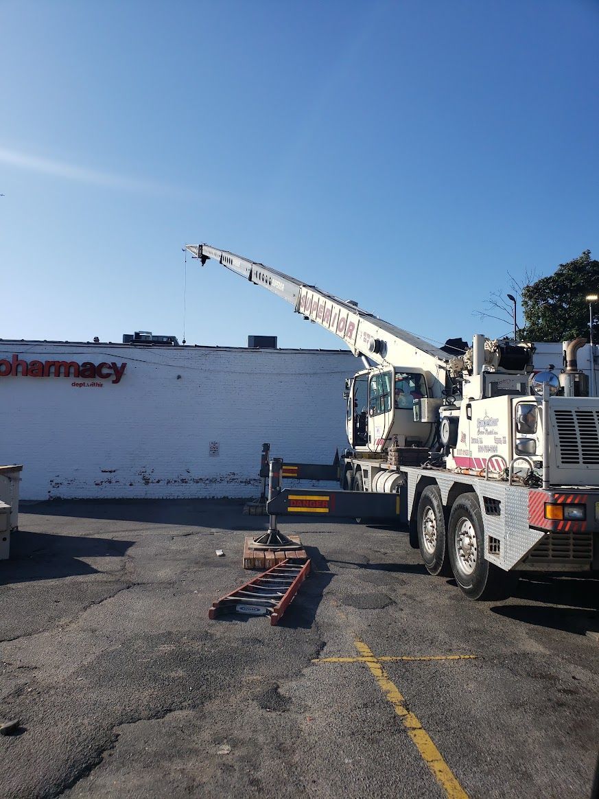 A crane is parked in front of a pharmacy in a parking lot.