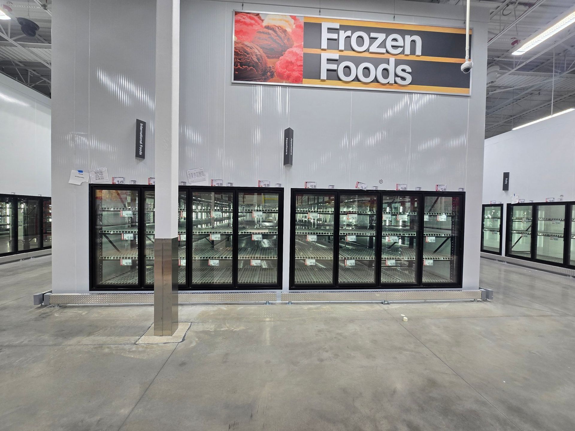 A frozen foods section of a store with a sign above it.