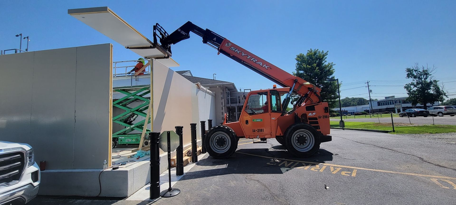 A forklift is lifting a concrete wall in a parking lot.