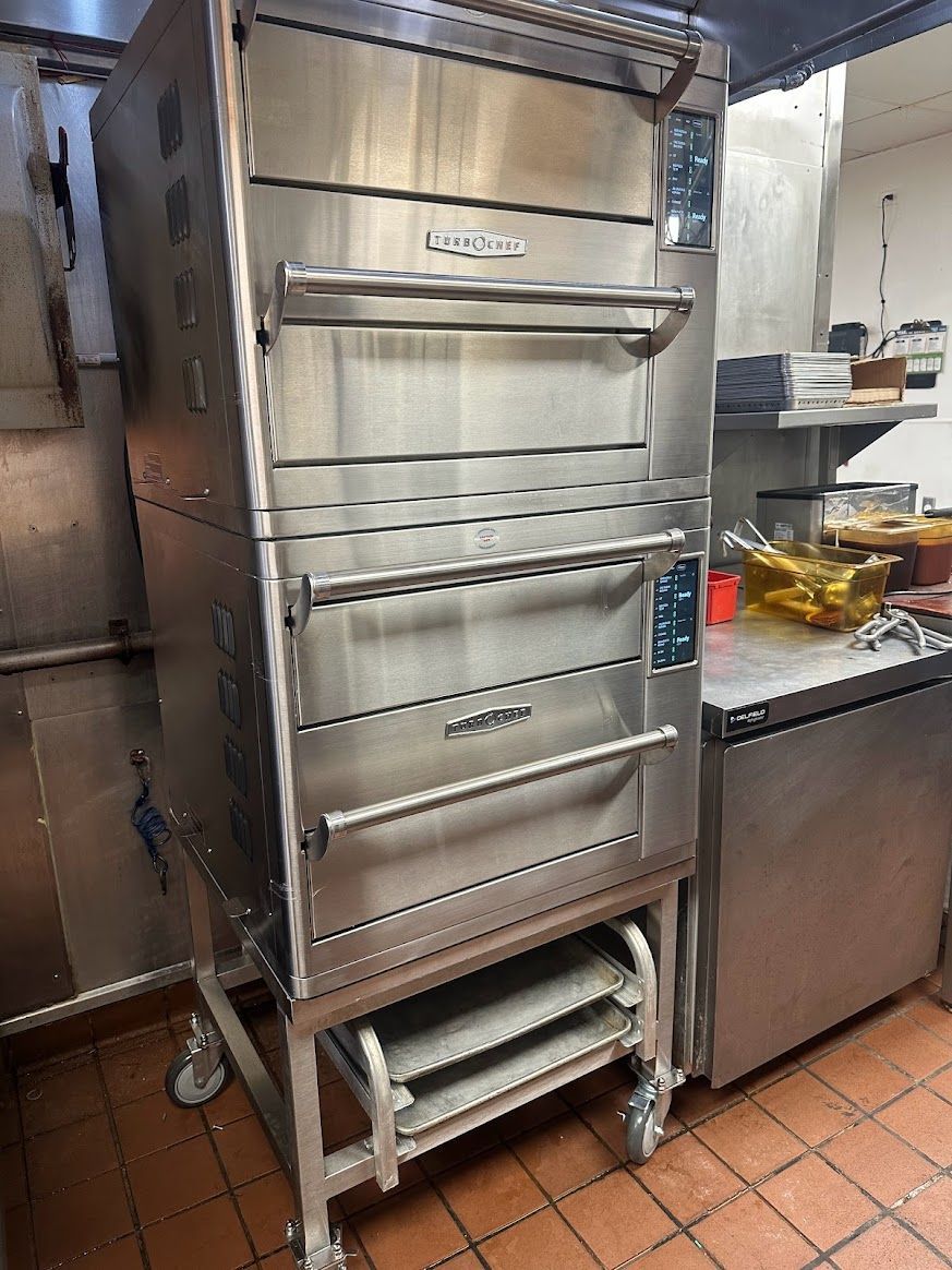 A stainless steel oven is sitting in a kitchen next to a refrigerator.