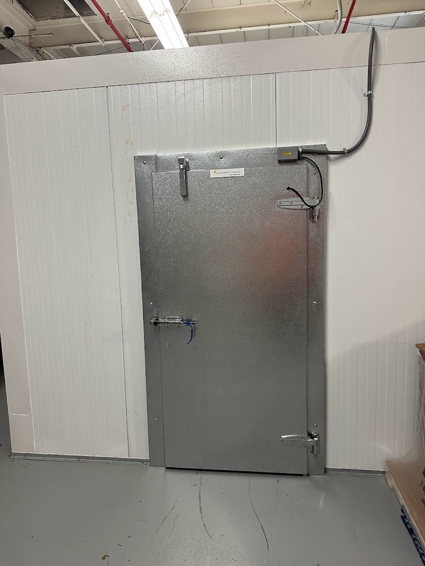 A metal door is hanging on a white wall in a room.