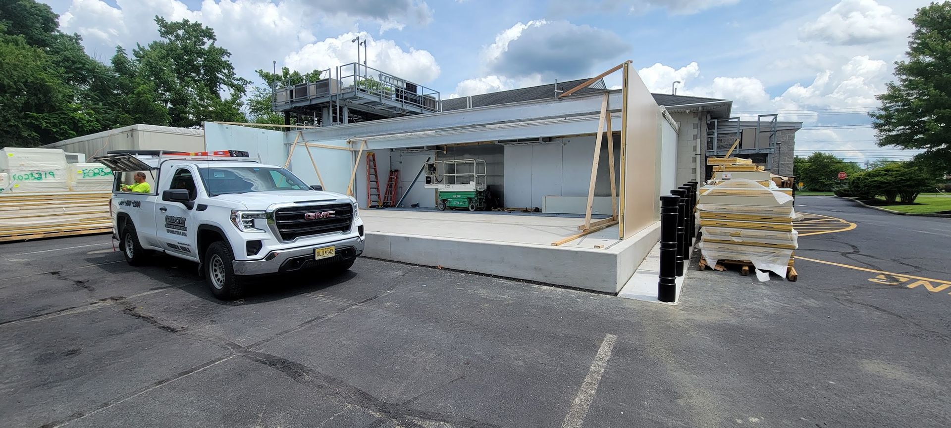 A white truck is parked in front of a building under construction.