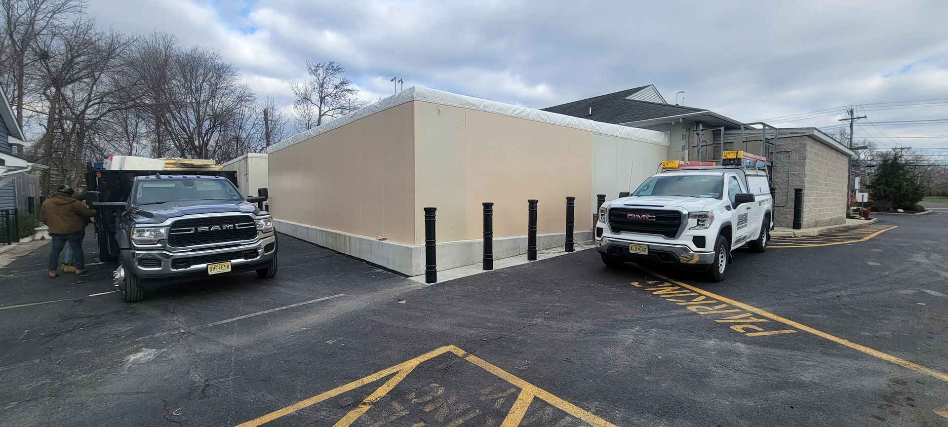 Two trucks are parked in front of a building in a parking lot.