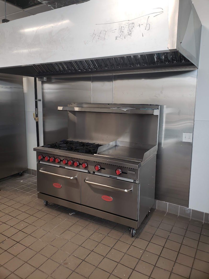 A large stainless steel stove is sitting in a kitchen.