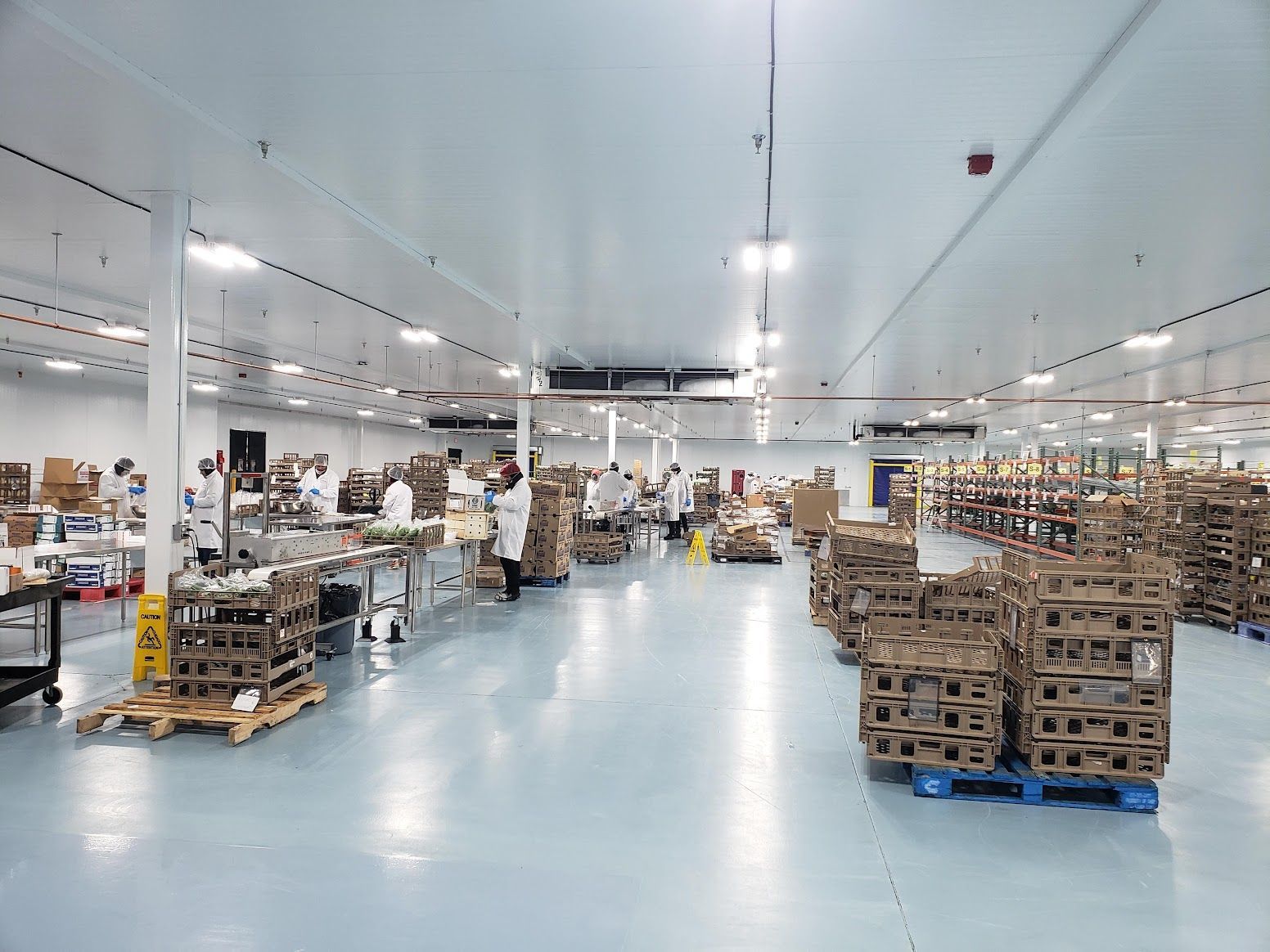 A large warehouse filled with lots of boxes and people.