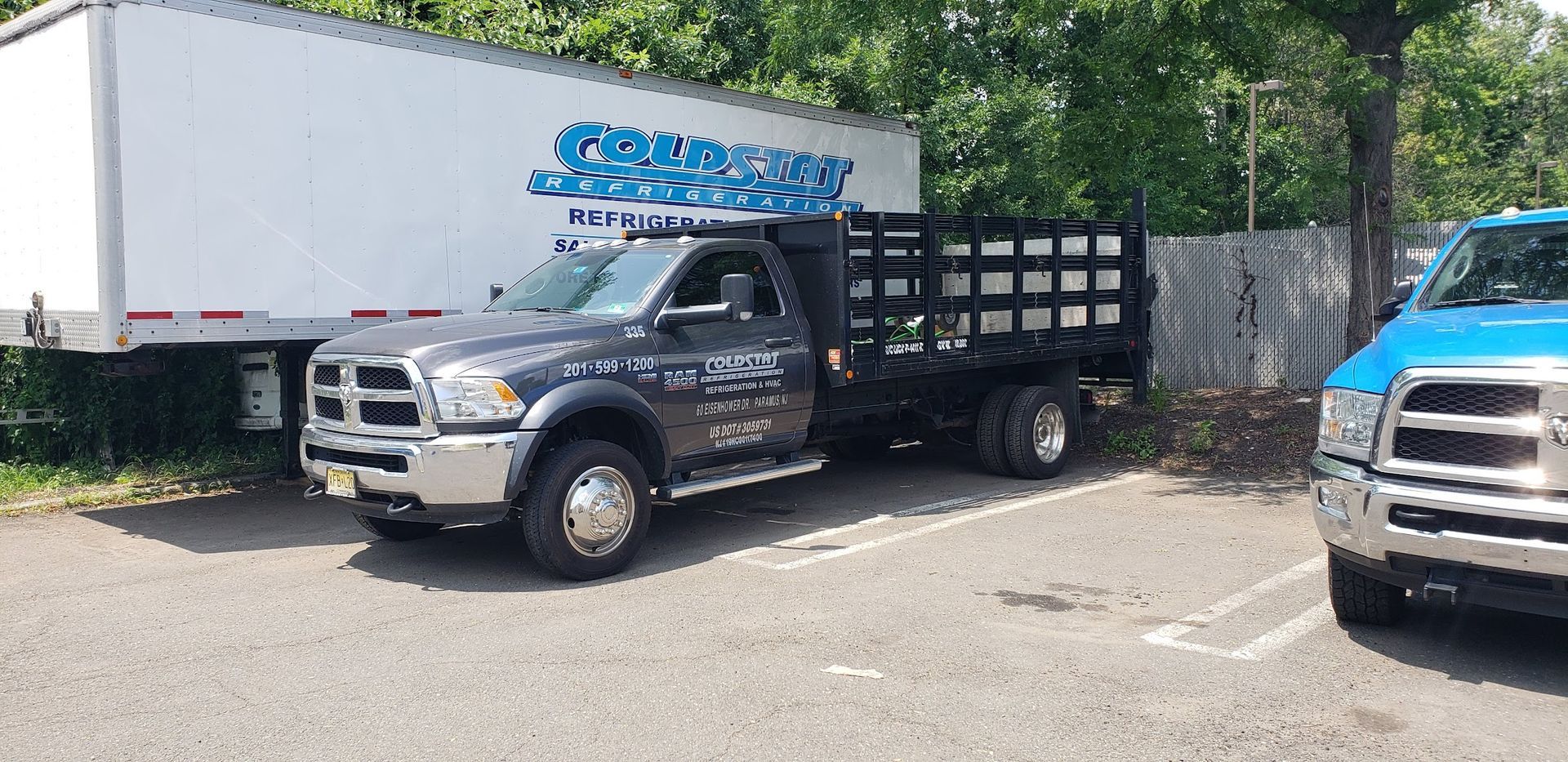 A truck is parked in a parking lot next to a white trailer.