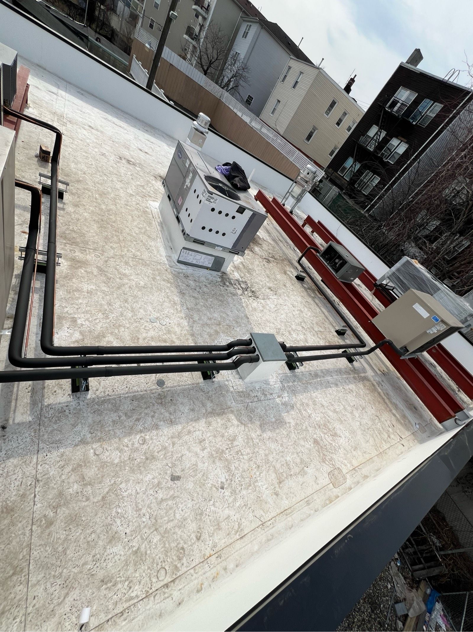 A roof with a lot of pipes on it and a building in the background.