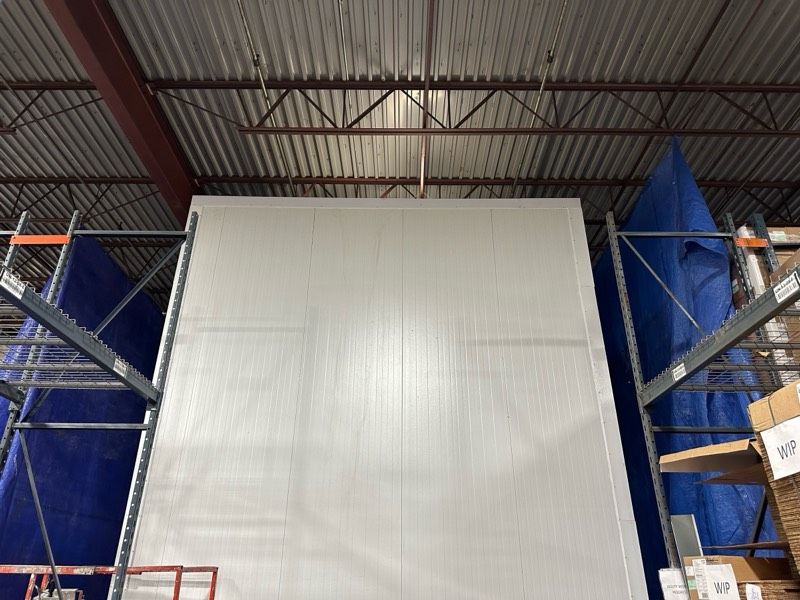 A large white wall is in the middle of a warehouse.