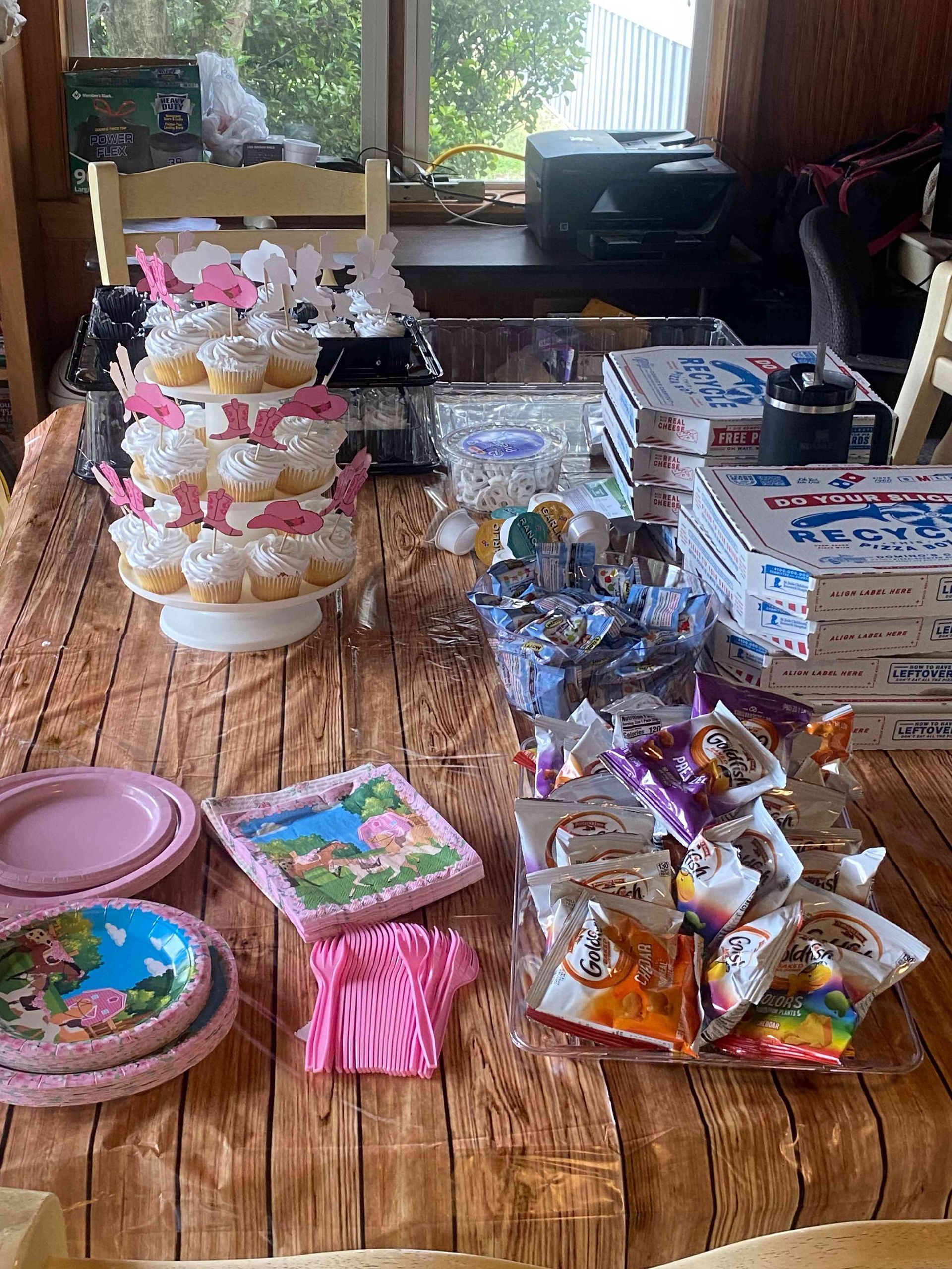 Decorated dessert table with cakes, cookies, candies, and boxed treats on a wooden floor