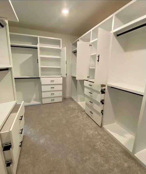 A walk in closet with lots of shelves and drawers