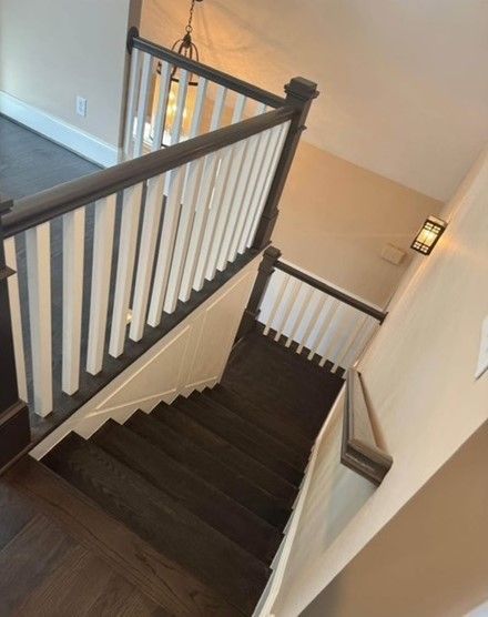 A staircase with a white railing and dark steps