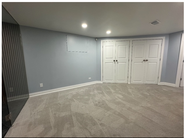 An empty room with a carpeted floor and white doors