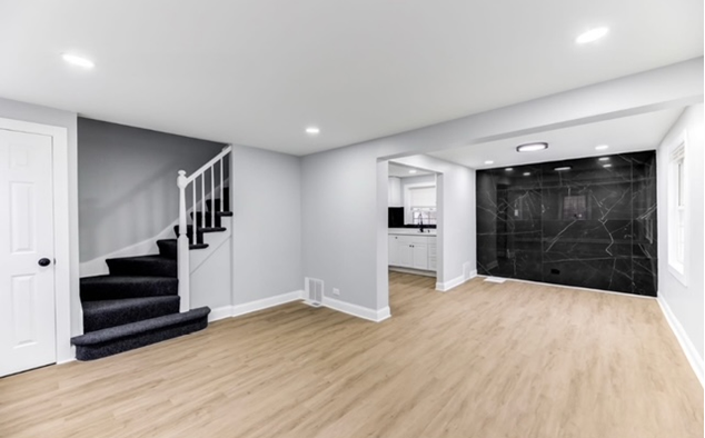 An empty living room with a kitchen in the background.