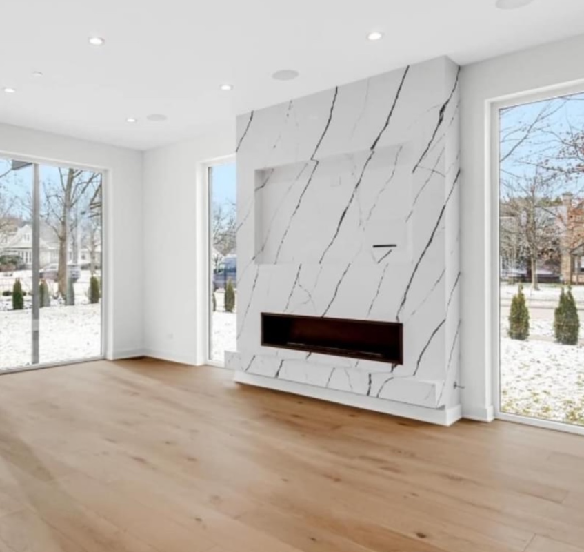 An empty living room with hardwood floors and a fireplace