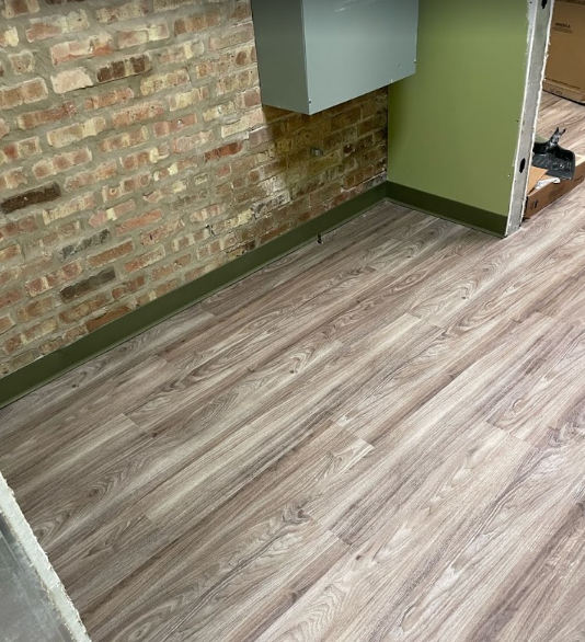 A room with a wooden floor and a brick wall.