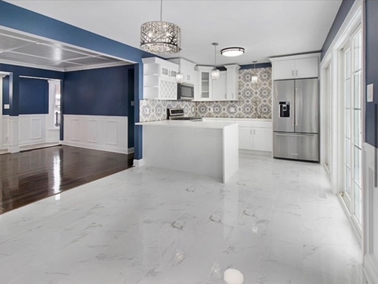 A kitchen with white cabinets and a stainless steel refrigerator