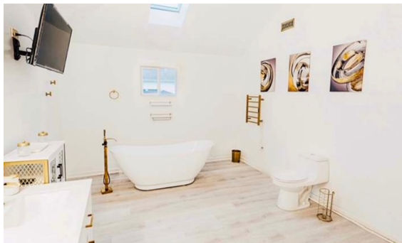 A bathroom with a tub , toilet , and television.