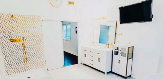 A bathroom with a sink , mirror and television.