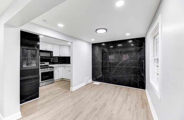 An empty basement with hardwood floors and stairs leading up to the second floor.