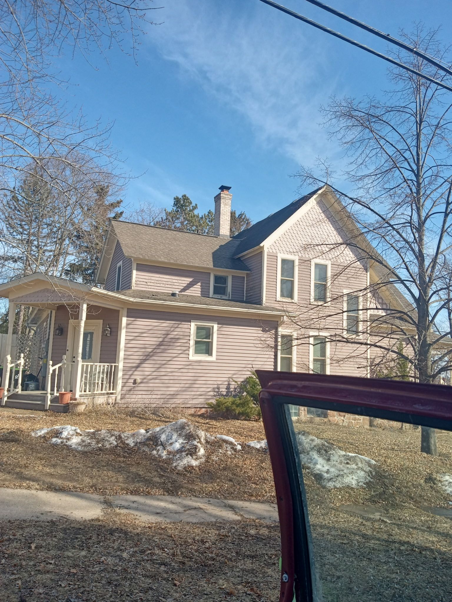 A pink house with a porch and a car parked in front of it.