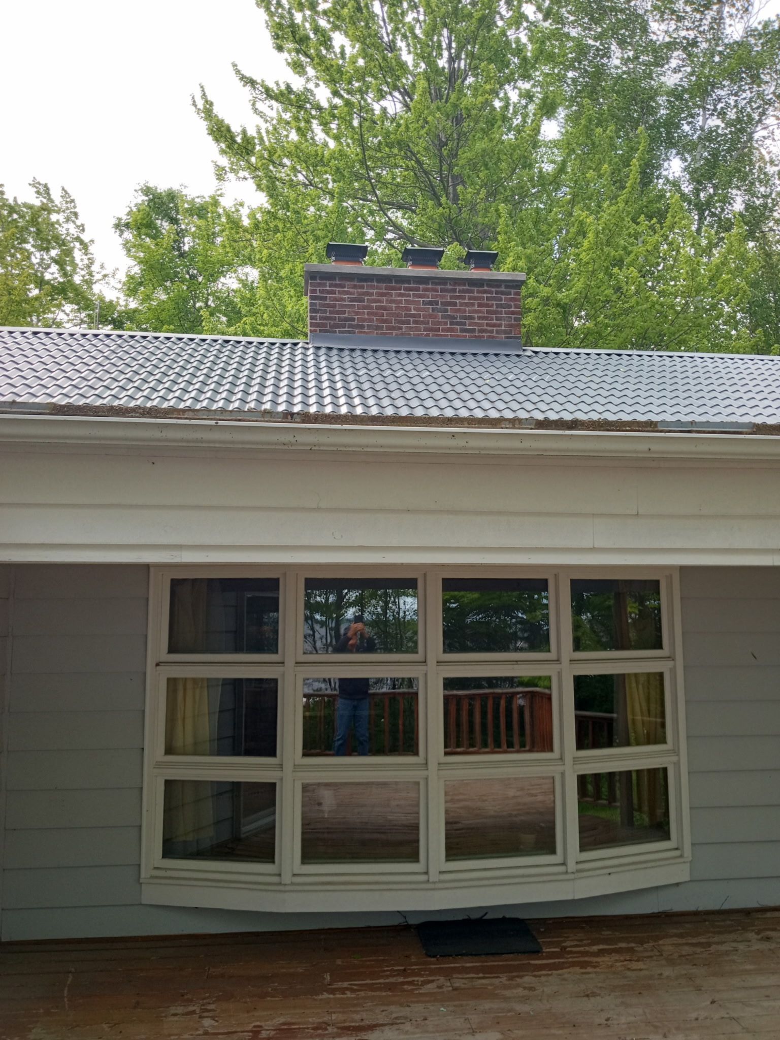 A white house with a large window and a chimney on the roof.