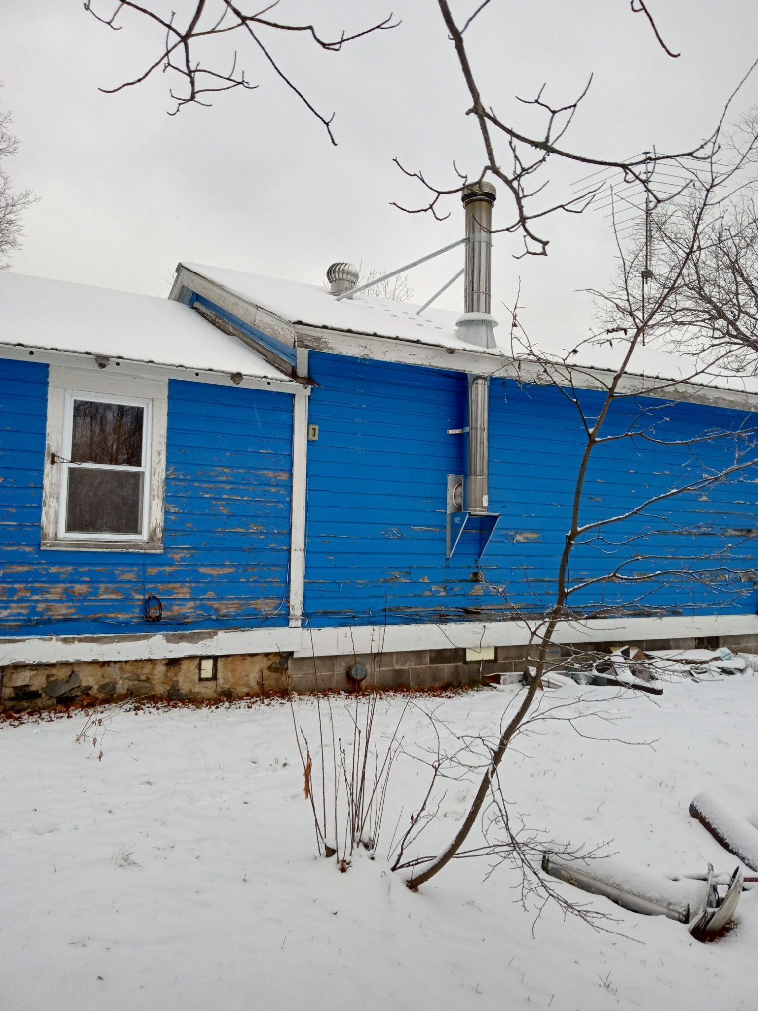 A blue house with a chimney in the snow.