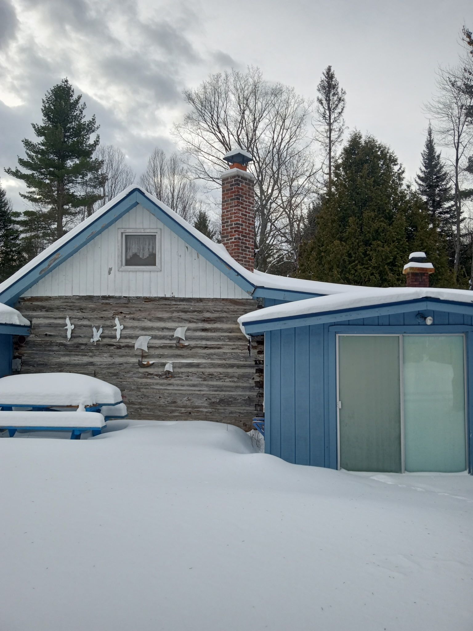 A blue and white house is covered in snow.