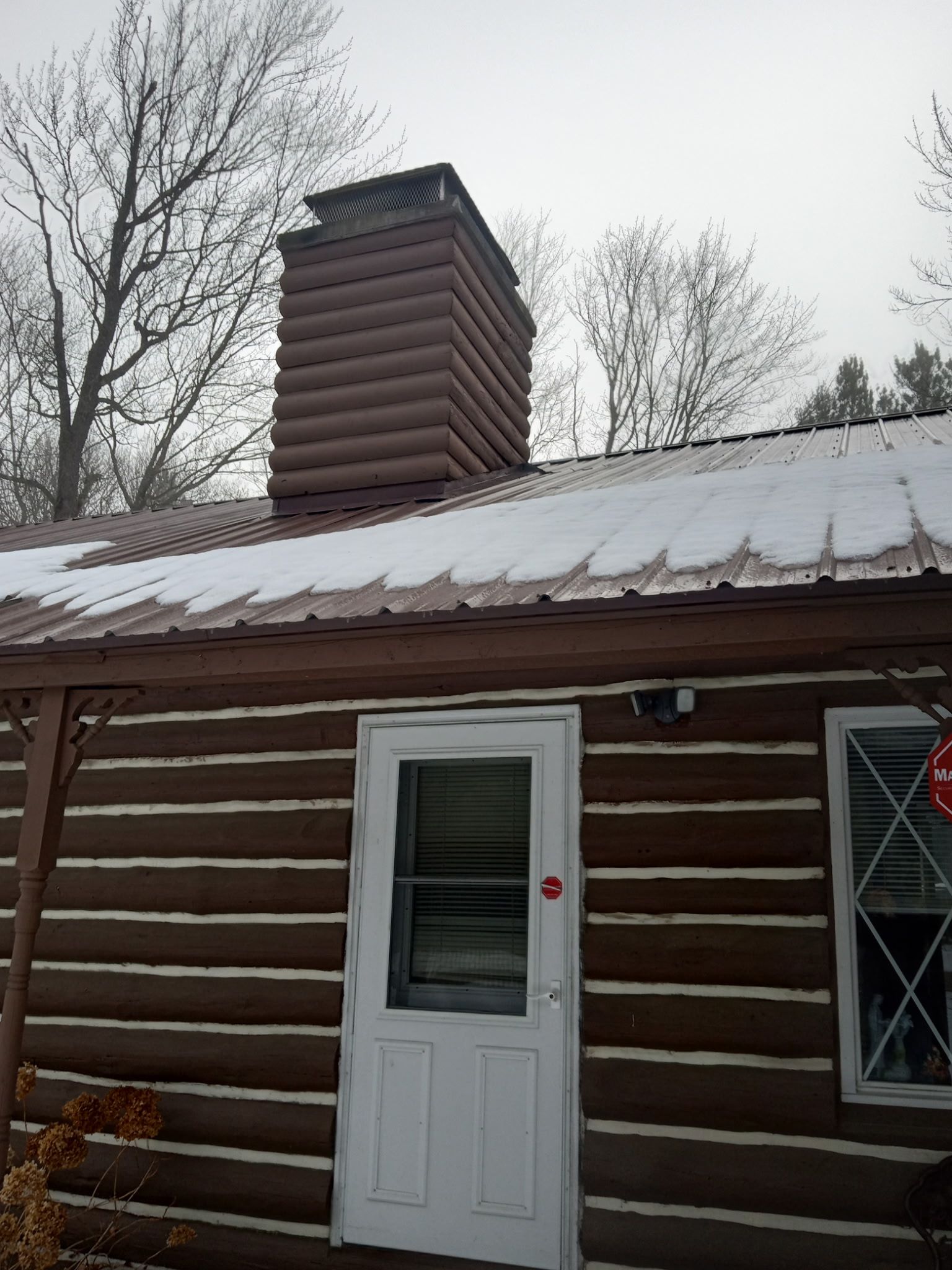 A log cabin with a white door and a chimney on the roof.