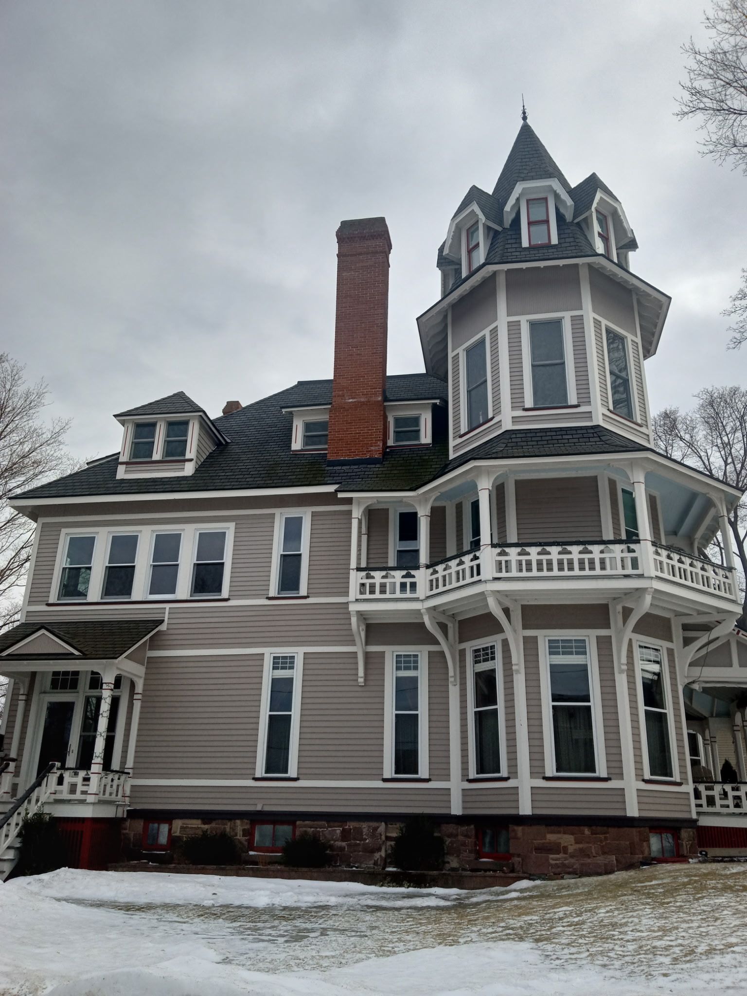 A large house with a tower on top of it is covered in snow.