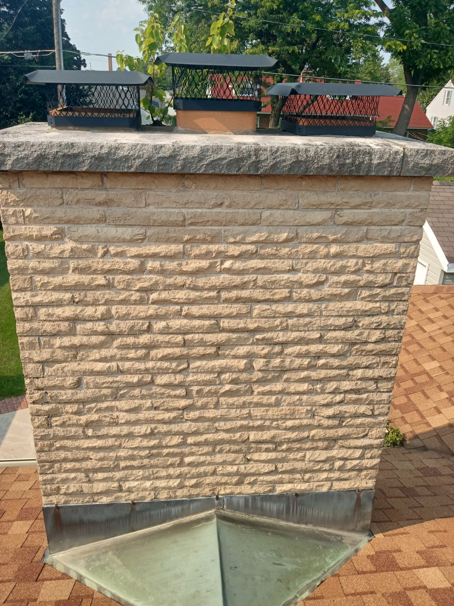 A brick chimney is sitting on top of a brick roof.