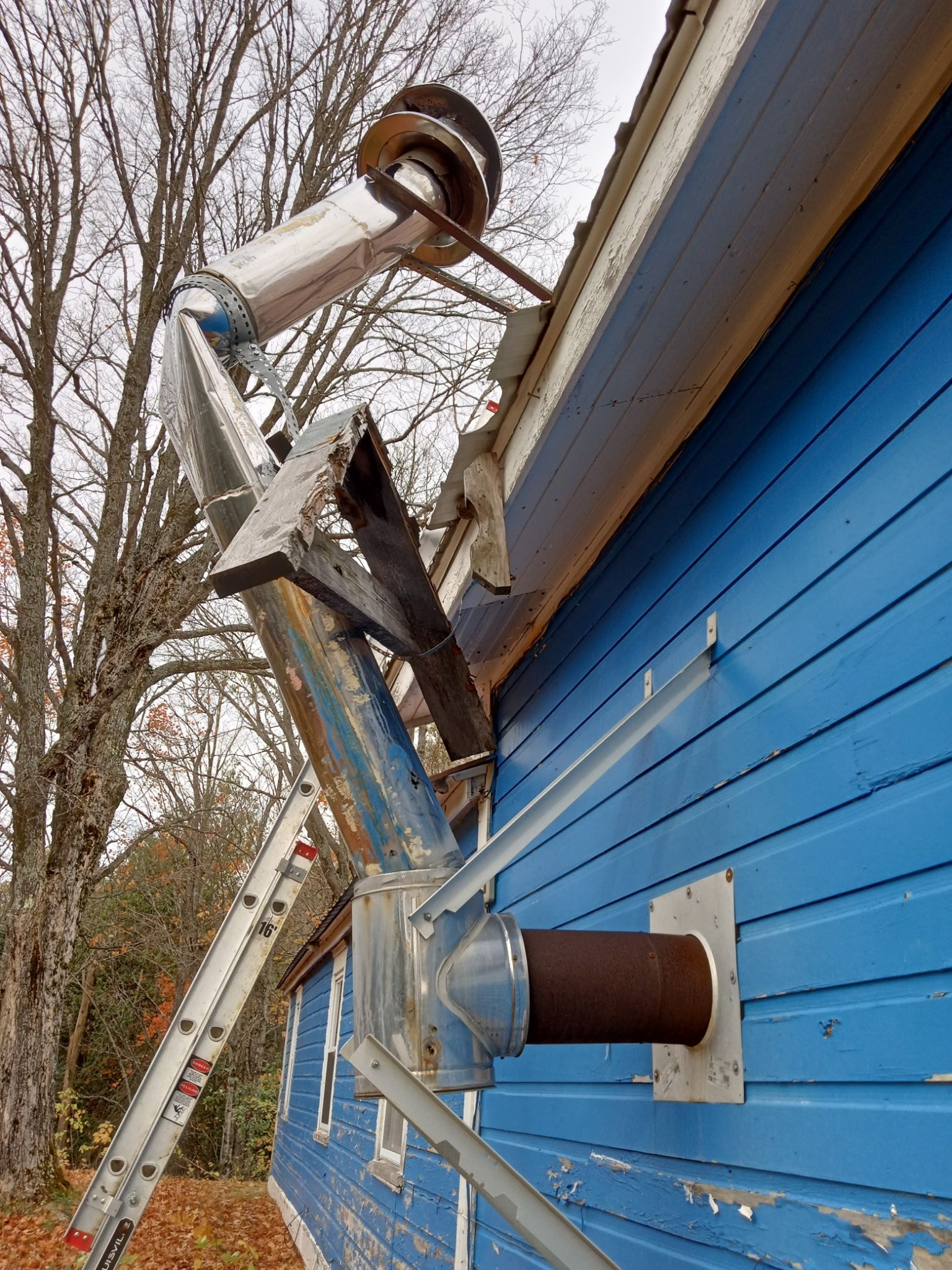 A blue house with a ladder attached to the side of it.