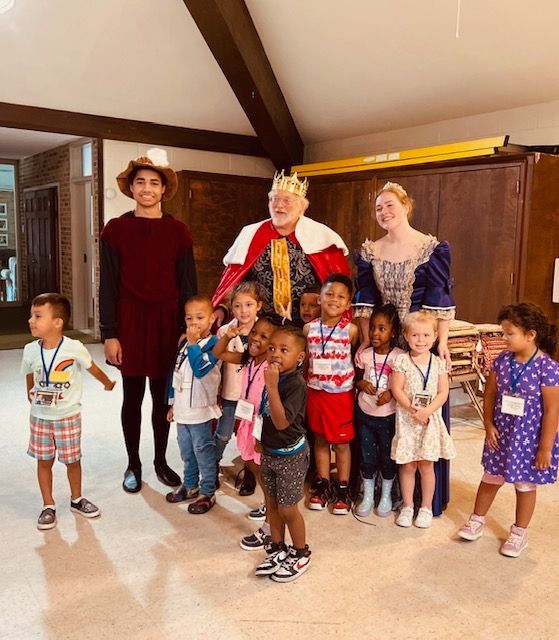 A group of children are posing for a picture with a man in a crown