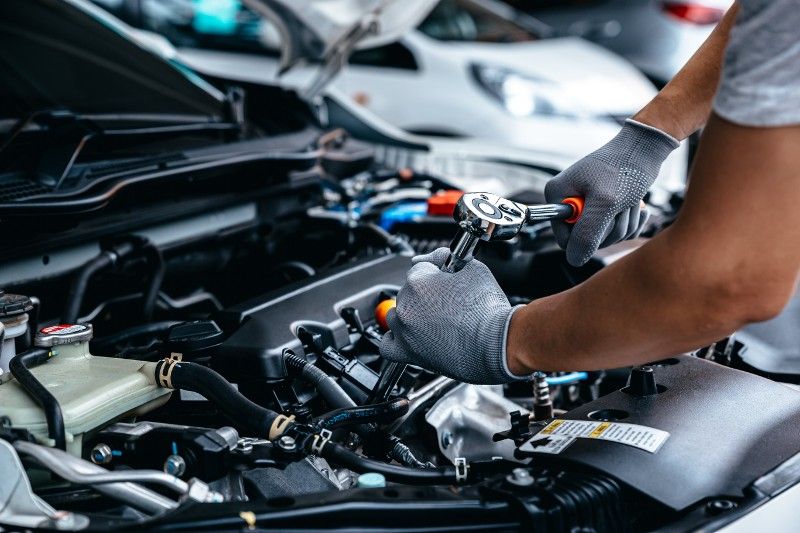 A man is working on the engine of a car with a wrench.