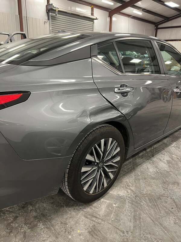 Gray sedan parked inside an auto shop, rear side view