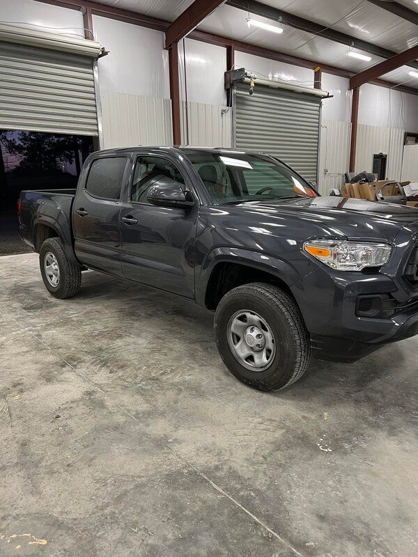 Dark gray pickup truck parked inside a metal garage with roll-up doors open to the outside.