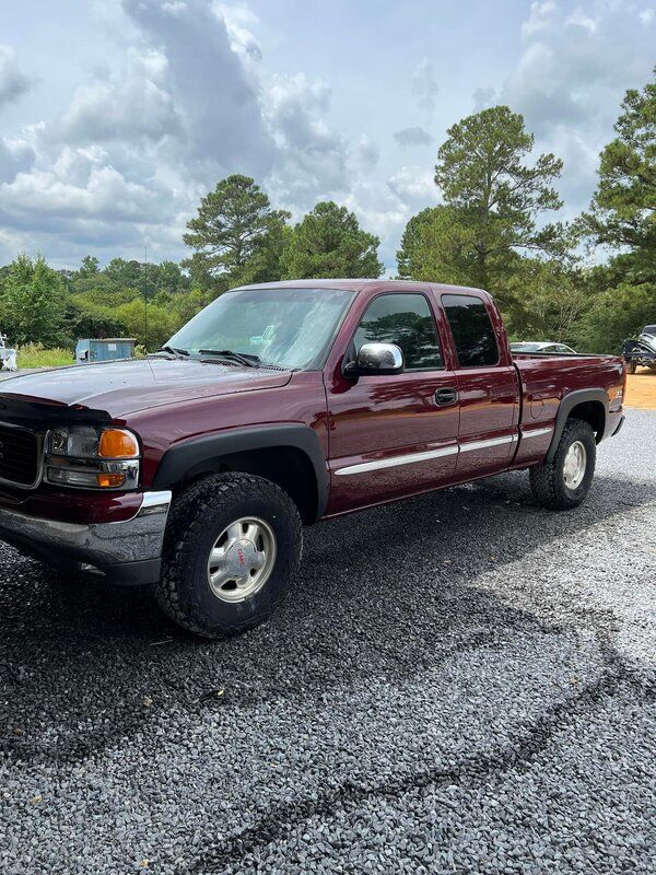 Maroon pickup truck parked on a gravel lot under a cloudy sky