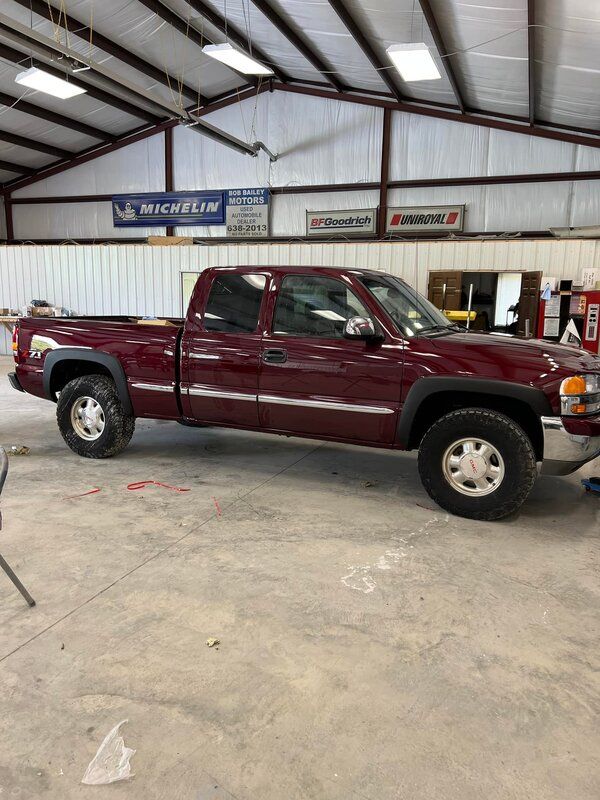 Maroon pickup truck parked inside a warehouse with a concrete floor and metal roof