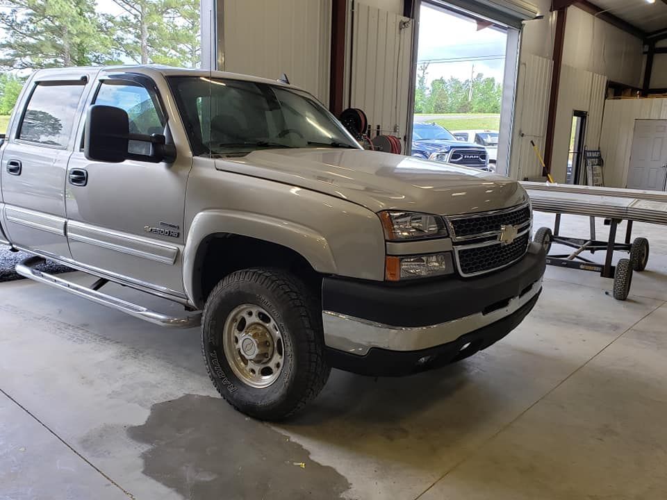 Silver pickup truck parked inside a garage near an open bay door.
