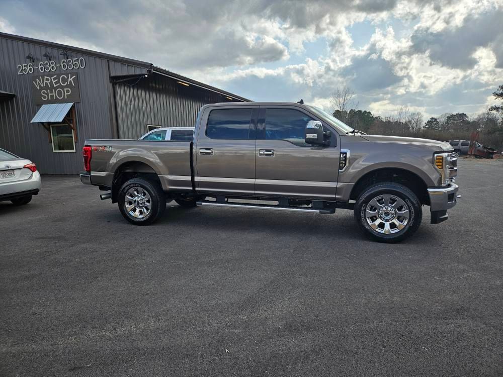 Gray pickup truck parked outside a rustic building on an asphalt lot under cloudy skies