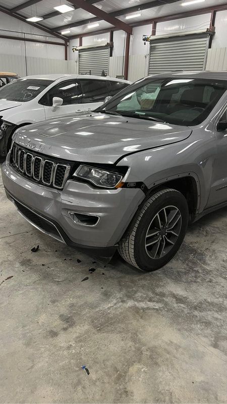 Gray Jeep SUV parked indoors in a garage beside other parked vehicles