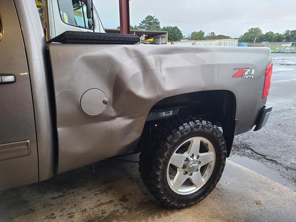Damaged gray pickup truck rear quarter panel with a large dent and Z71 badge in a parking lot