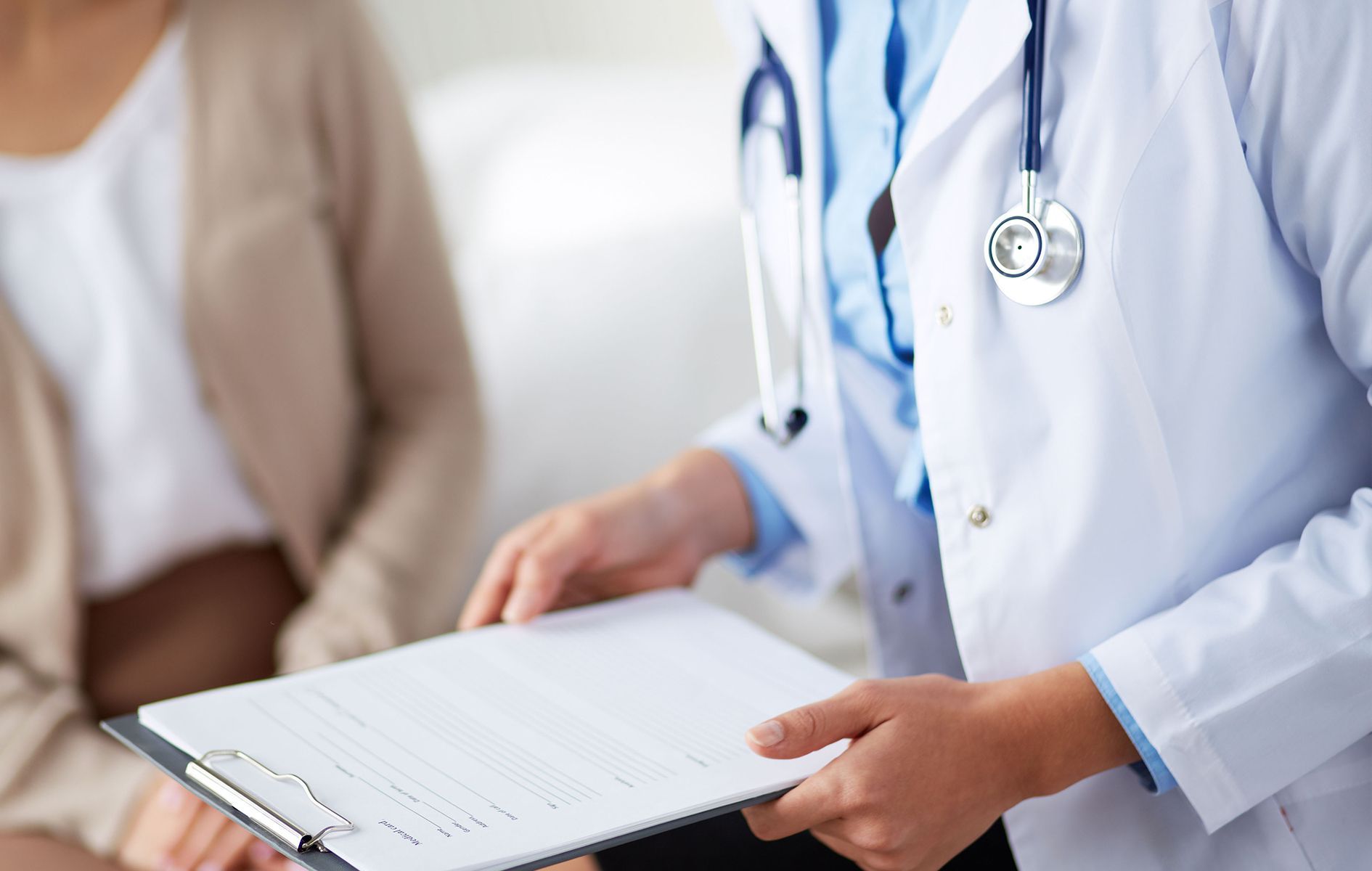 A doctor is holding a clipboard in front of a patient.