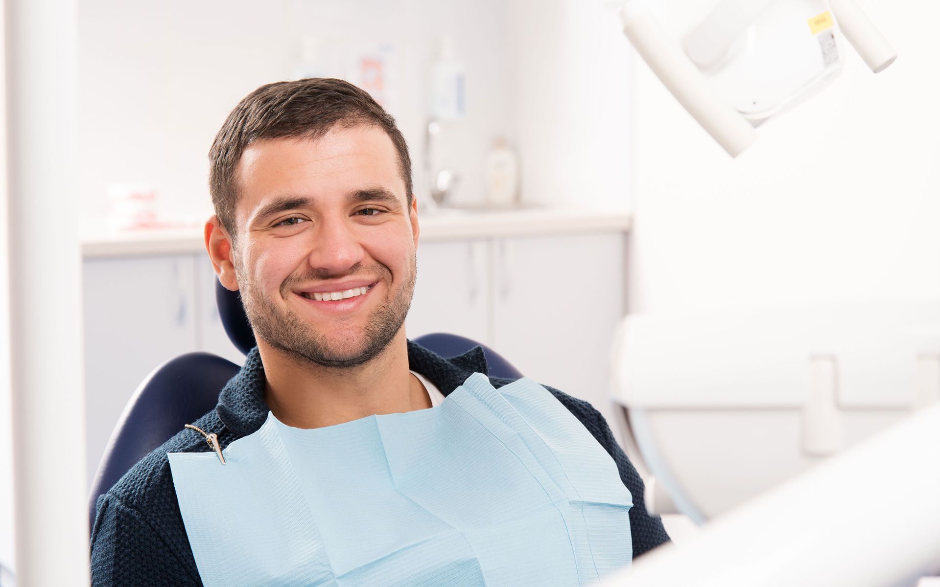 a man is smiling while sitting in a dental chair