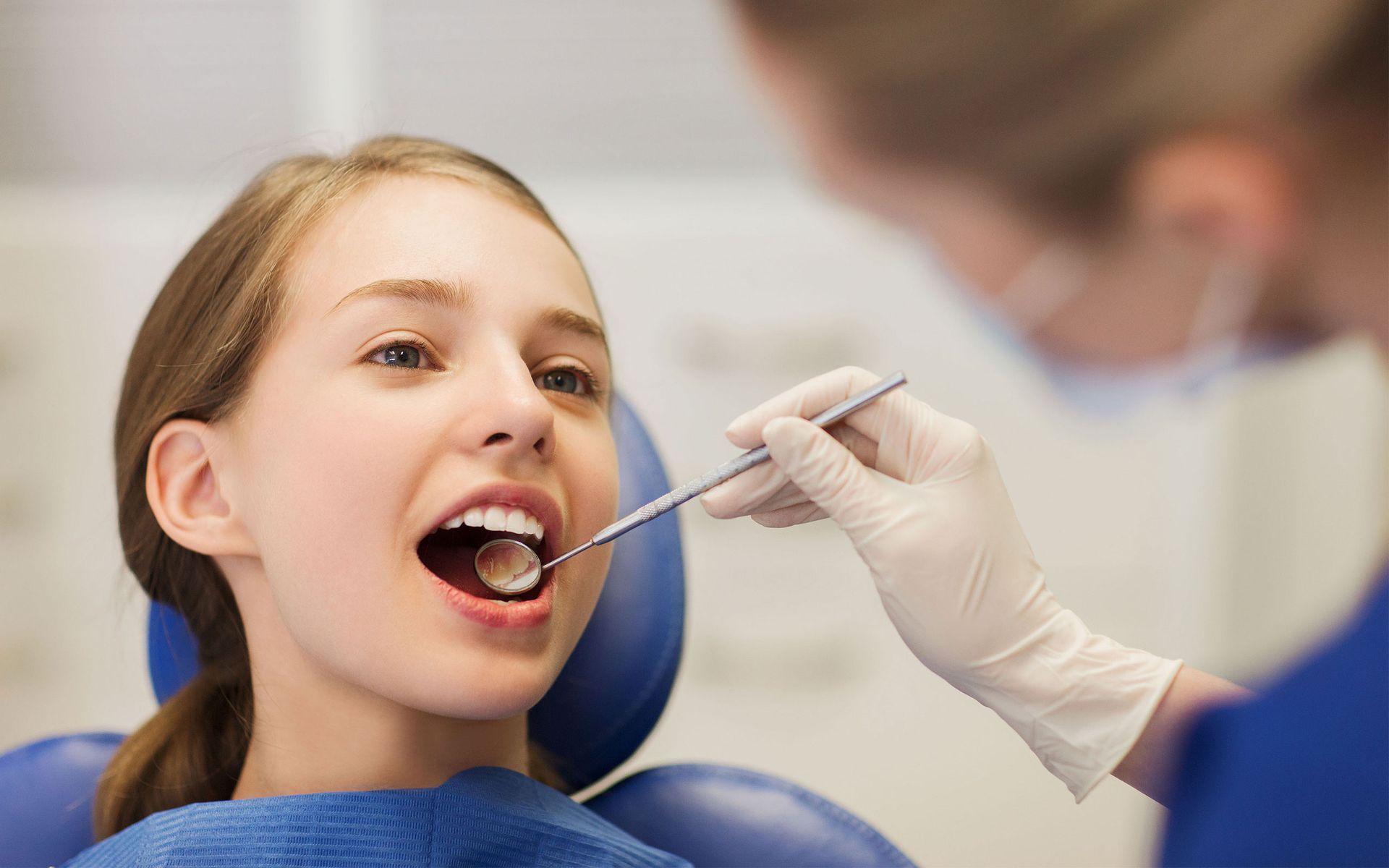 a young girl is getting her teeth examined by a dentist