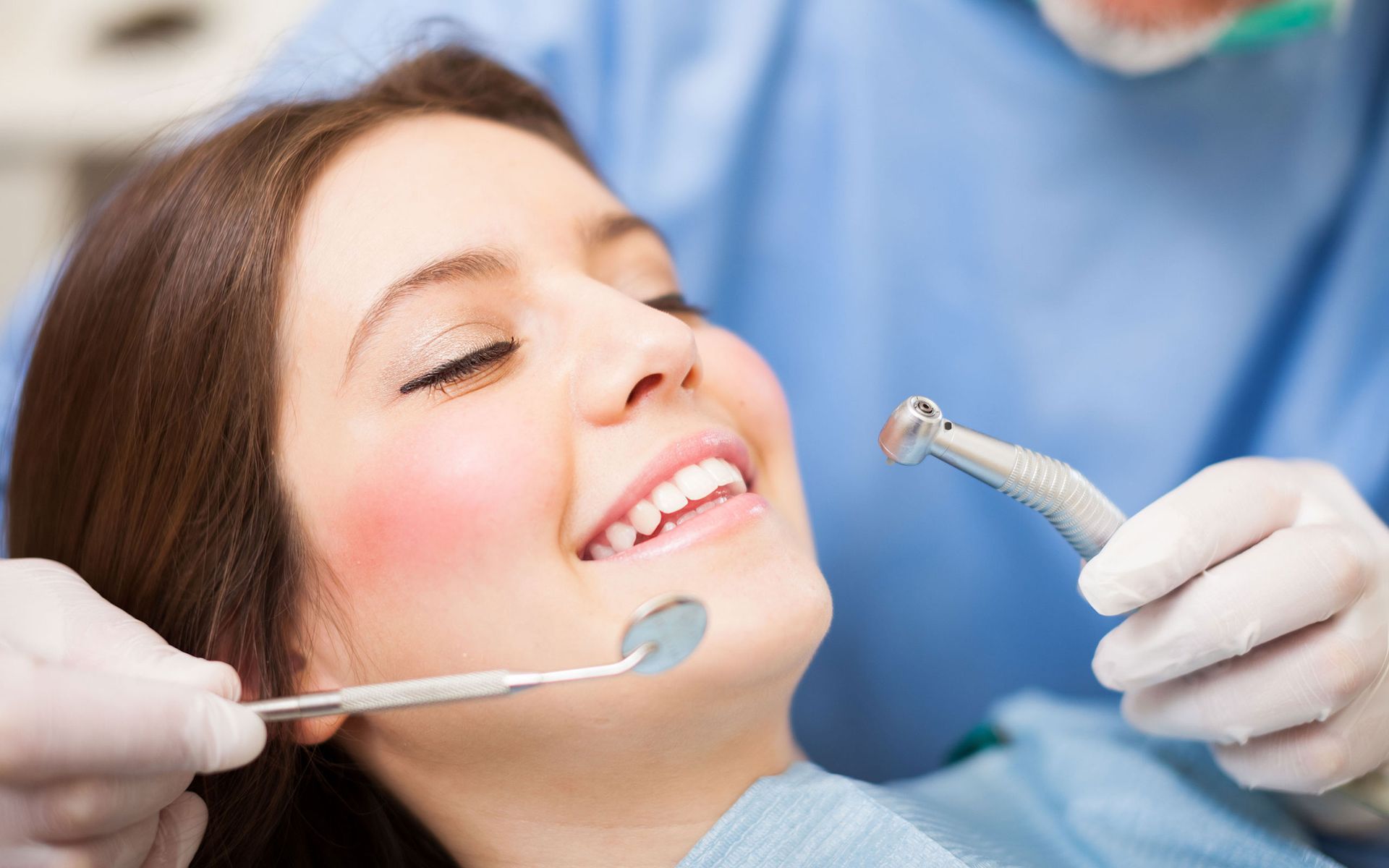 a woman is getting her teeth examined by a dentist